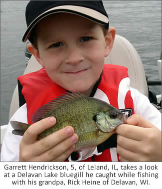Garrett Hendrickson, 5, of Leland, Ill., takes a look at a Delavan Lake bluegill he caught while fishing with his grandpa, Rick Heine of Delavan, Wis.